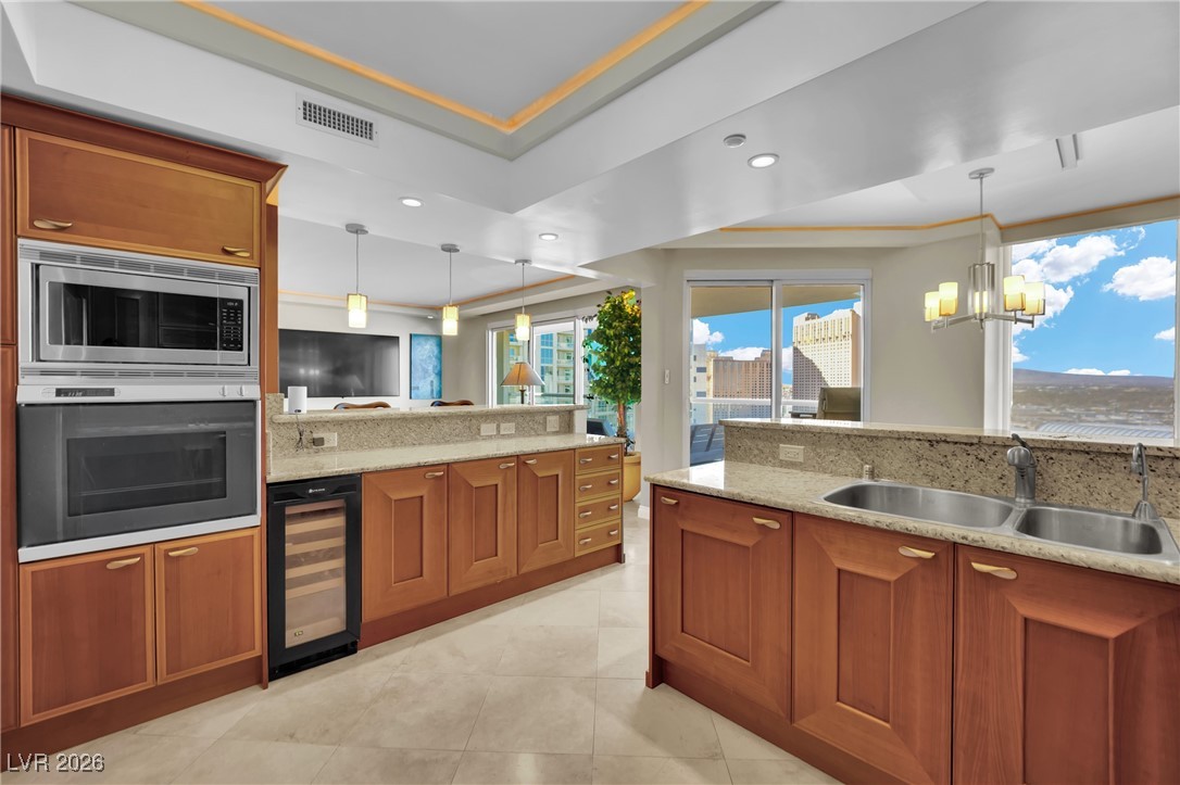 2777 Paradise Road, Unit 1803 Las Vegas, NV 89109 - Photo 8 of 48 Kitchen featuring brown cabinetry, a tray ceiling, stainless steel appliances, and recessed lighting