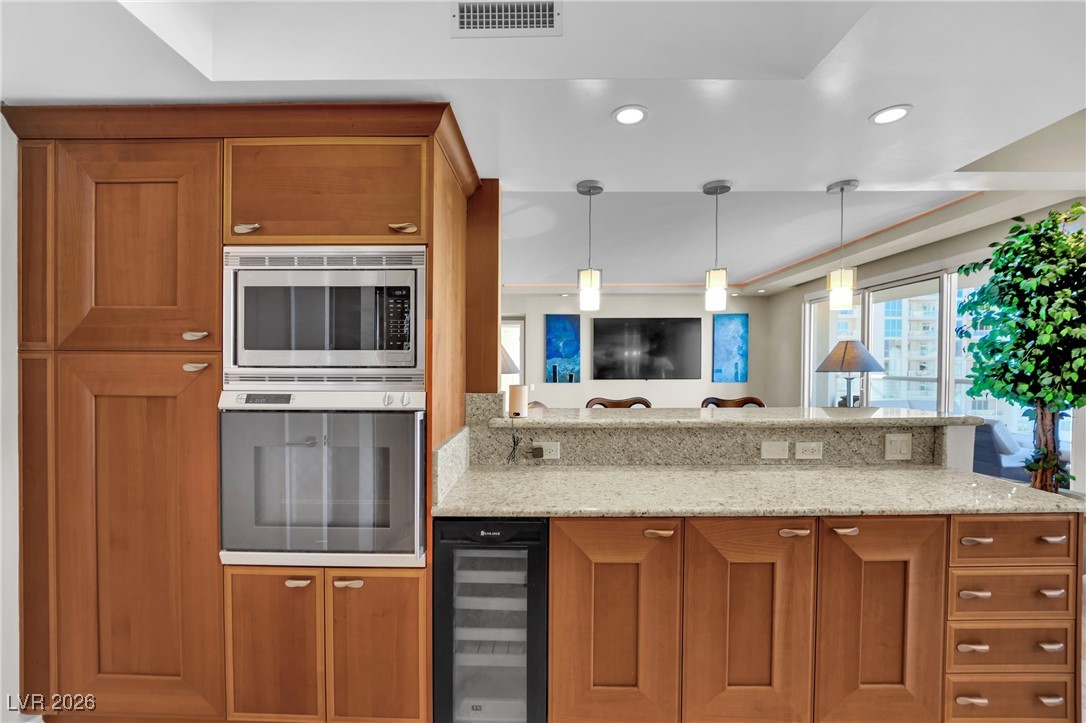 2777 Paradise Road, Unit 1803 Las Vegas, NV 89109 - Photo 10 of 48 Kitchen with brown cabinetry, wine cooler, light stone countertops, stainless steel appliances, and recessed lighting