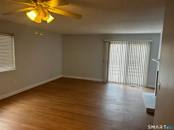 an empty room with wooden floor fireplace and windows
