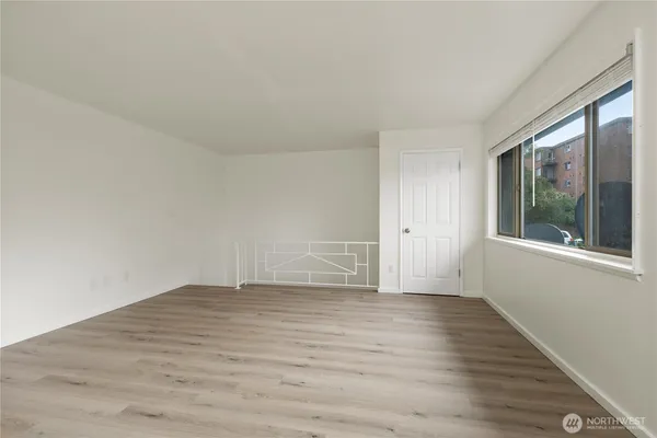 a view of an empty room with wooden floor and a window