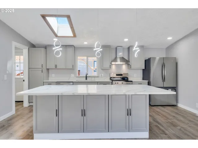 a kitchen with stainless steel appliances granite countertop a sink a stove a refrigerator and a oven