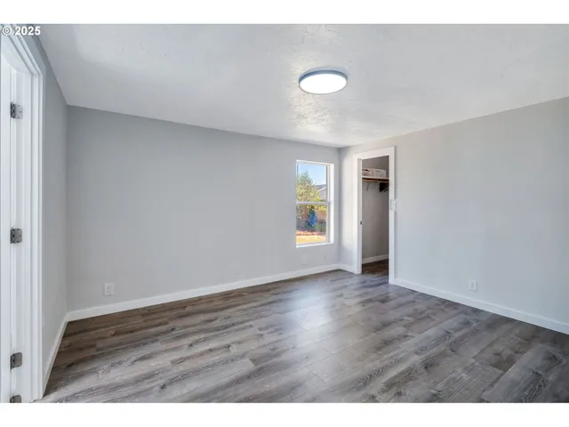 a view of an empty room with window and wooden floor