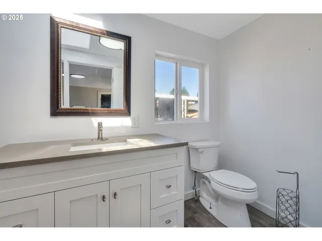a bathroom with a granite countertop sink a toilet and a mirror