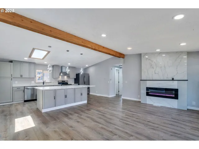 a open kitchen with stainless steel appliances granite countertop a refrigerator a sink dishwasher a stove and white countertops with wooden floor