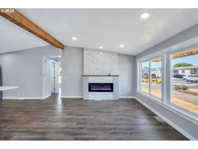 a view of an empty room with window and wooden floor