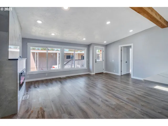a view of an empty room with wooden floor and fan