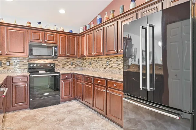 a kitchen with stainless steel appliances granite countertop a refrigerator and a stove top oven