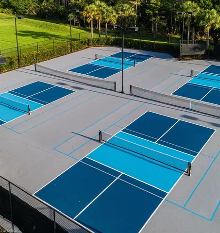 a view of a tennis ground with large trees