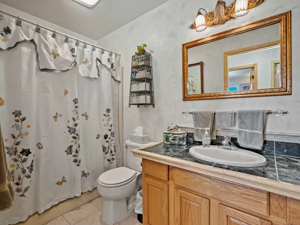 a bathroom with a granite countertop sink mirror vanity and toilet