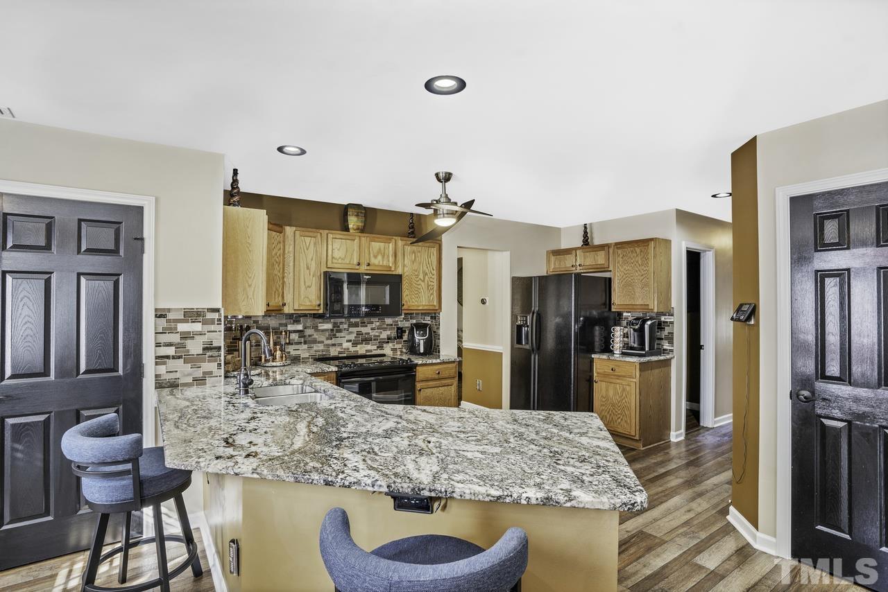 4704 Jelynn Street Raleigh, NC 27616 - Photo 10 of 30 a kitchen with stainless steel appliances kitchen island granite countertop a table chairs in it and a living room