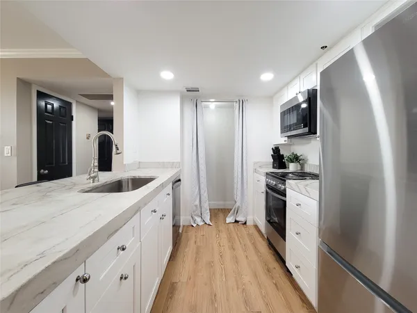 a kitchen with granite countertop a sink stove and refrigerator