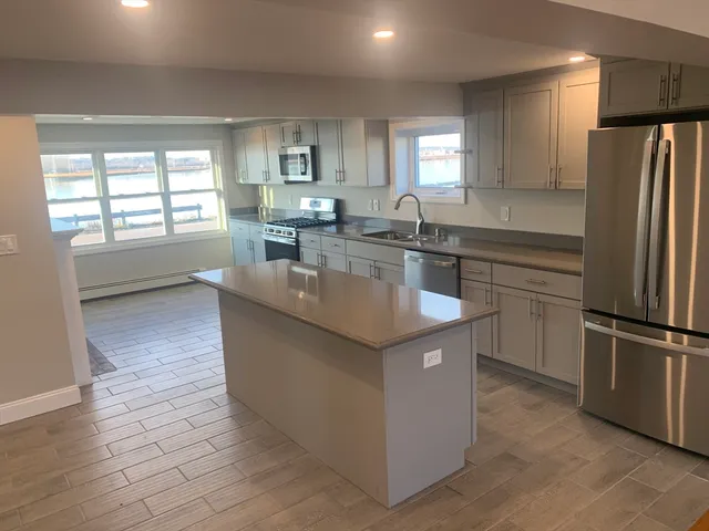 a kitchen with kitchen island a sink a counter top space stainless steel appliances and a window
