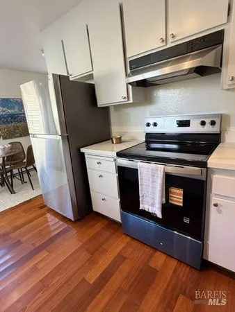 a kitchen with stainless steel appliances wooden floor sink and wooden cabinets