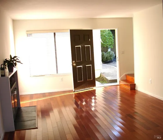 a view of empty room with wooden floor and floor to ceiling window