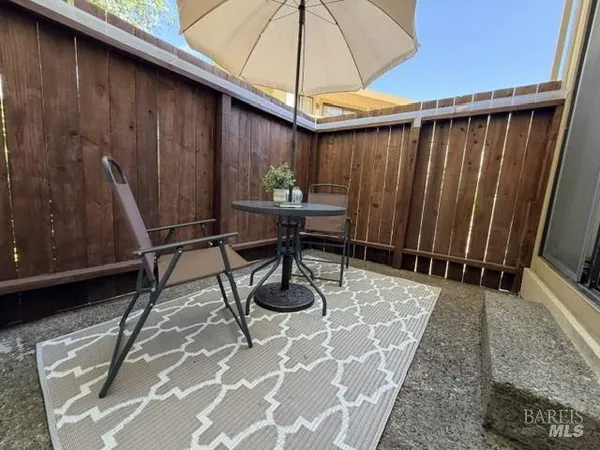a table and chairs in patio with wooden fence