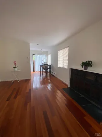 a view of a room with wooden floor and two windows