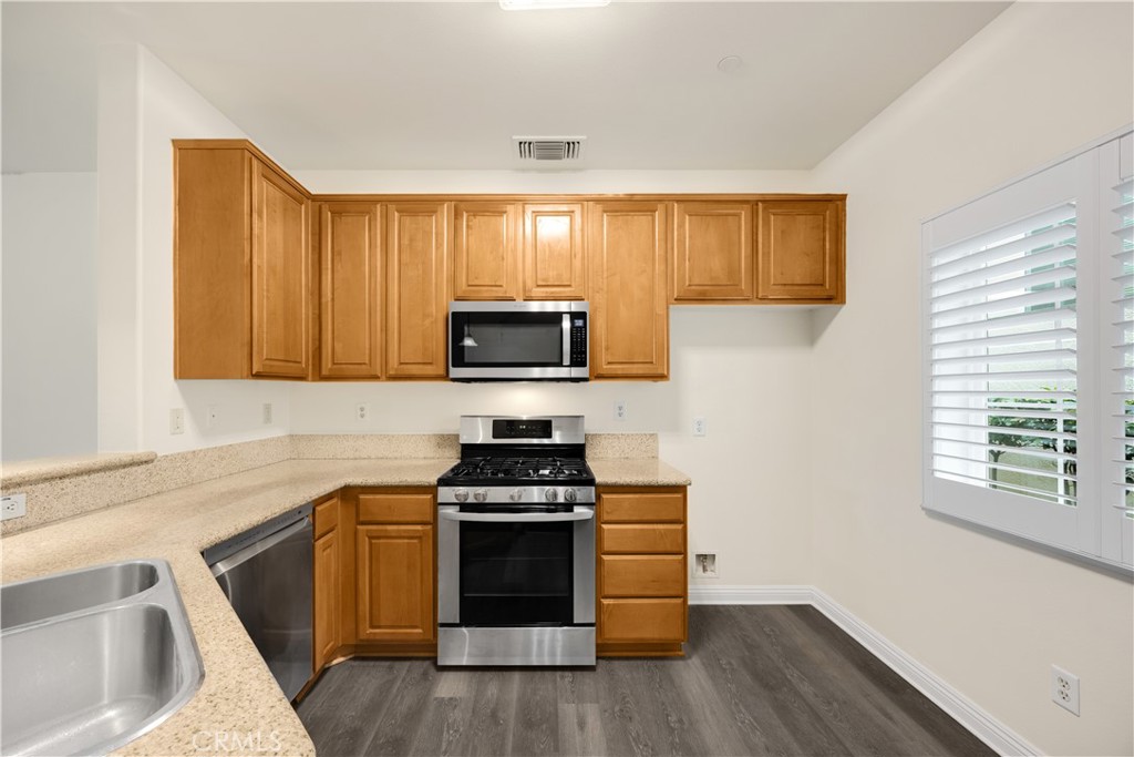 93 Kansas Street, Unit 705 Redlands, CA 92373 - Photo 13 of 33 a kitchen with granite countertop wooden floors and stainless steel appliances