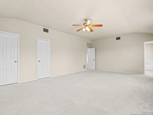 an empty room with a chandelier fan and wooden floor