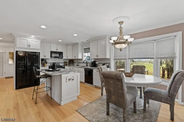 a kitchen with stainless steel appliances granite countertop a dining table chairs refrigerator and microwave