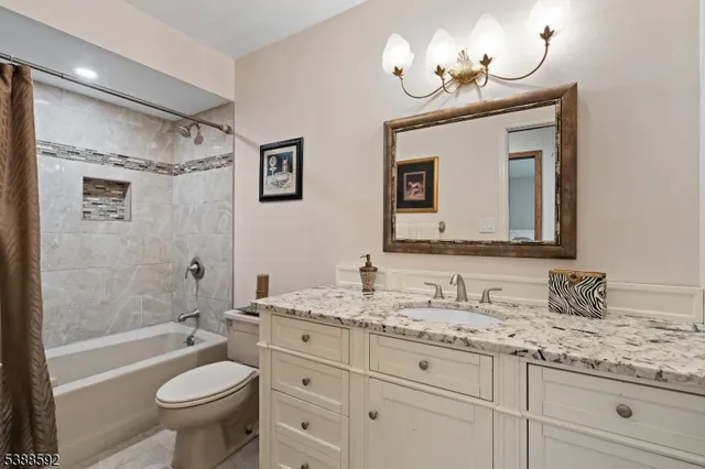 a bathroom with a granite countertop sink a toilet a mirror a bathtub and shower