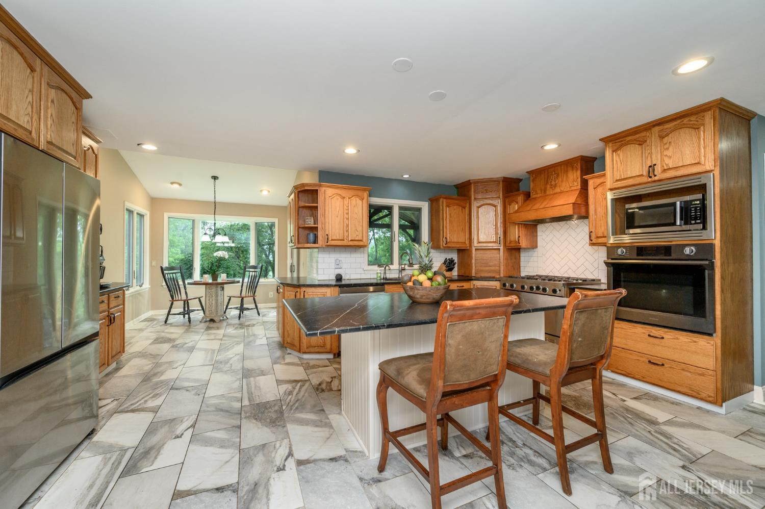 16 Pinewood Lane Washington, NJ 07882 - Photo 26 of 45 a kitchen with stainless steel appliances a dining table chairs and a refrigerator