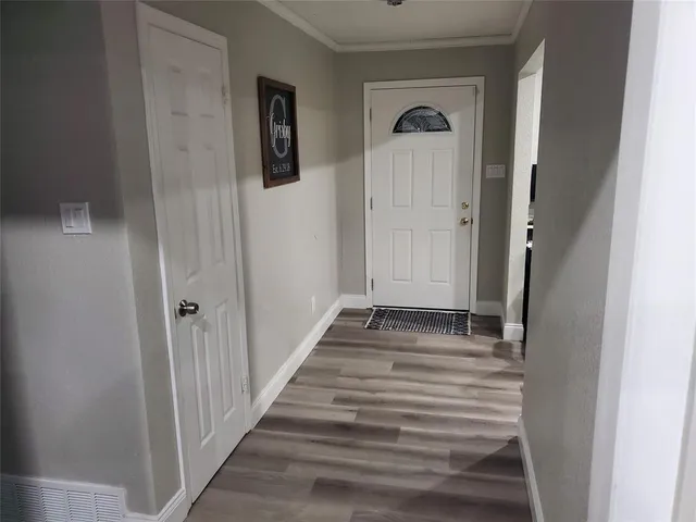 a view of a hallway with wooden floor and a cabinet