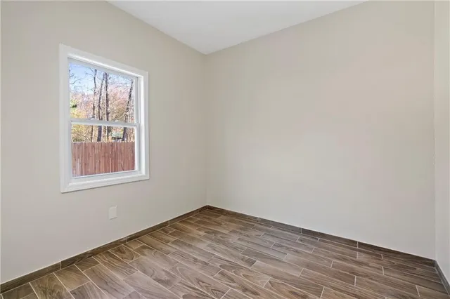 a view of an empty room with wooden floor and a window