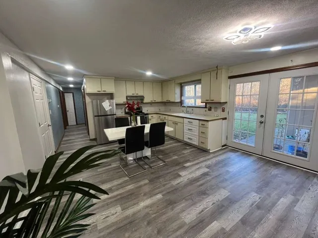 a living room with stainless steel appliances granite countertop furniture wooden floor and a view of kitchen