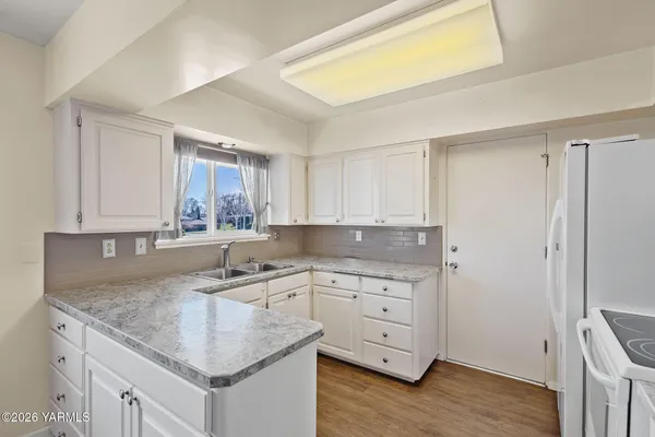a kitchen with white cabinets and window