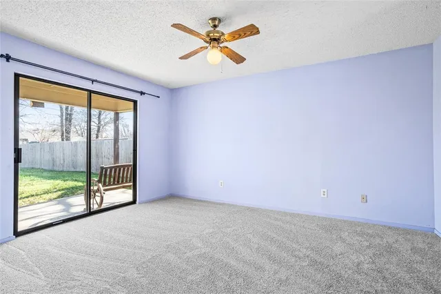 an empty room with windows and ceiling fan