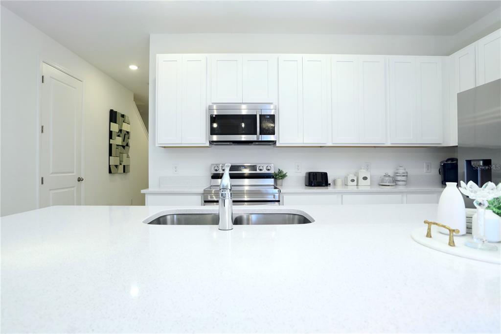 943 Conch Road Davenport, FL 33896 - Photo 12 of 43 a kitchen with stainless steel appliances granite countertop a sink and a stove