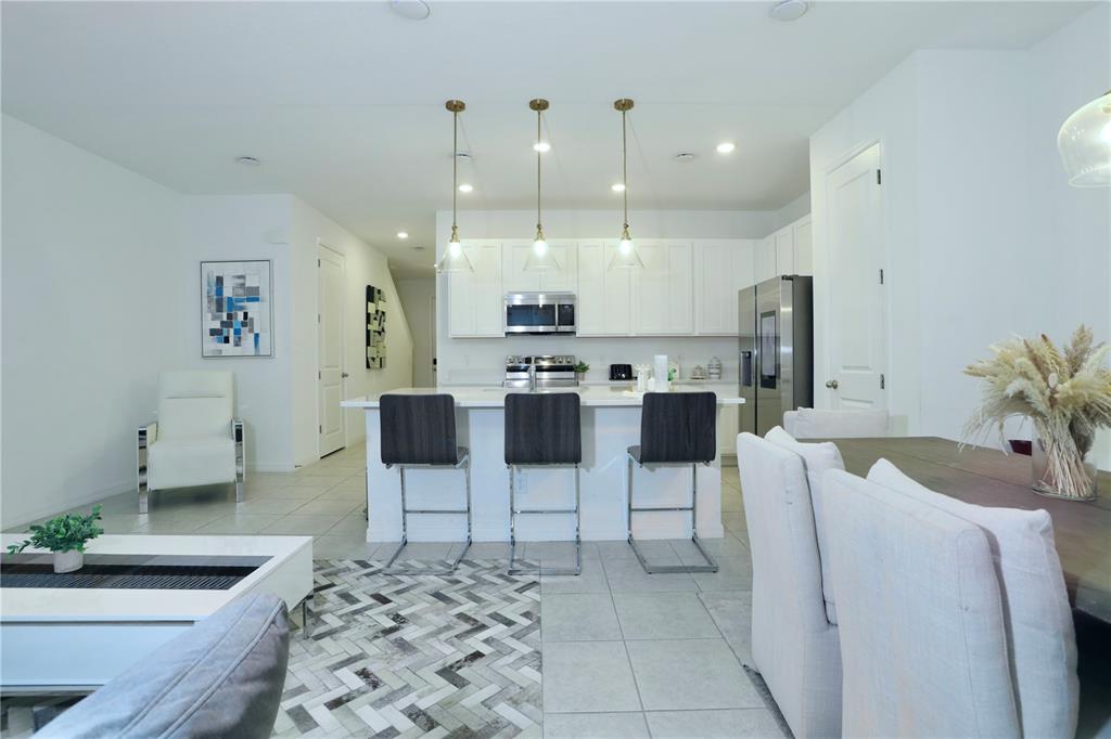 943 Conch Road Davenport, FL 33896 - Photo 9 of 43 a living room with furniture a chandelier and kitchen view