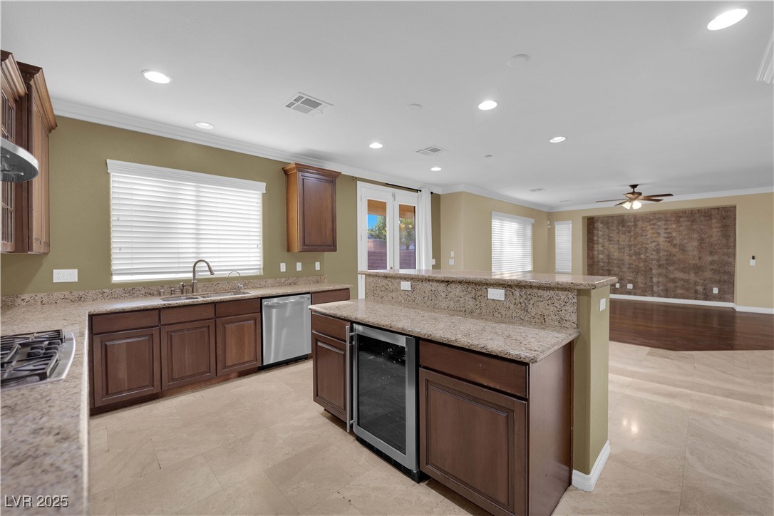 10057 Portula Valley Street Las Vegas, NV 89178 - Photo 11 of 56 Kitchen with crown molding, recessed lighting, wine cooler, light stone countertops, and appliances with stainless steel finishes