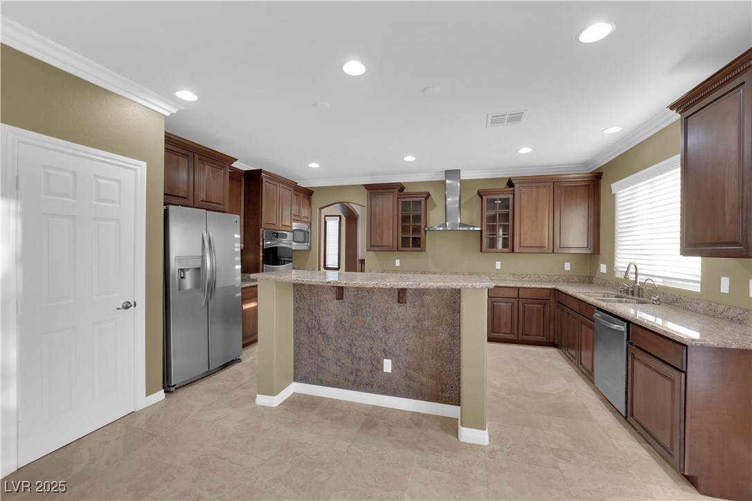 10057 Portula Valley Street Las Vegas, NV 89178 - Photo 16 of 56 Kitchen featuring a kitchen breakfast bar, glass insert cabinets, appliances with stainless steel finishes, light stone countertops, and arched walkways