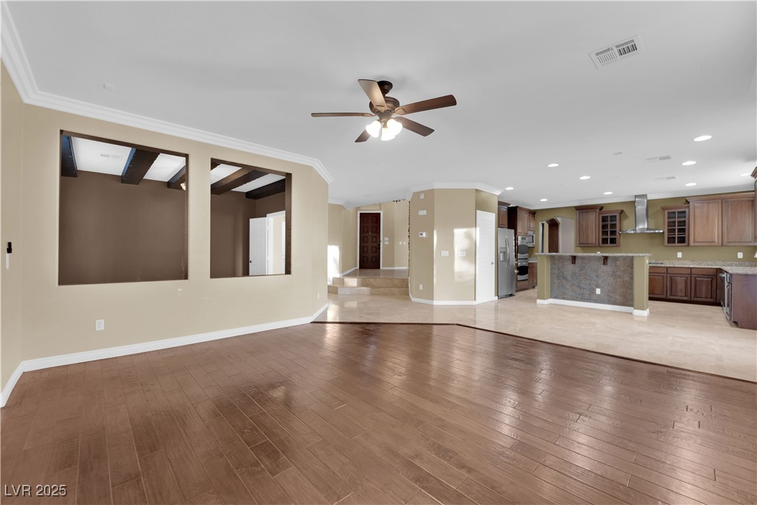 10057 Portula Valley Street Las Vegas, NV 89178 - Photo 21 of 56 Unfurnished living room with crown molding, light wood-style floors, ceiling fan, and recessed lighting