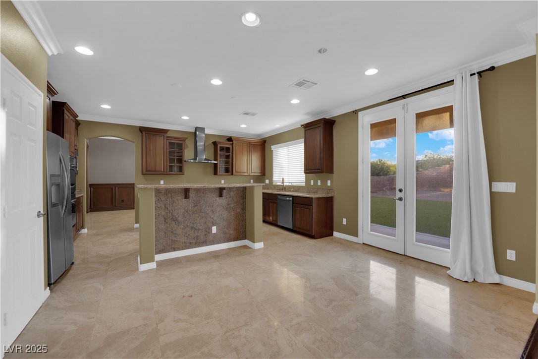 10057 Portula Valley Street Las Vegas, NV 89178 - Photo 22 of 56 Kitchen featuring glass insert cabinets, ornamental molding, arched walkways, french doors, and a kitchen island