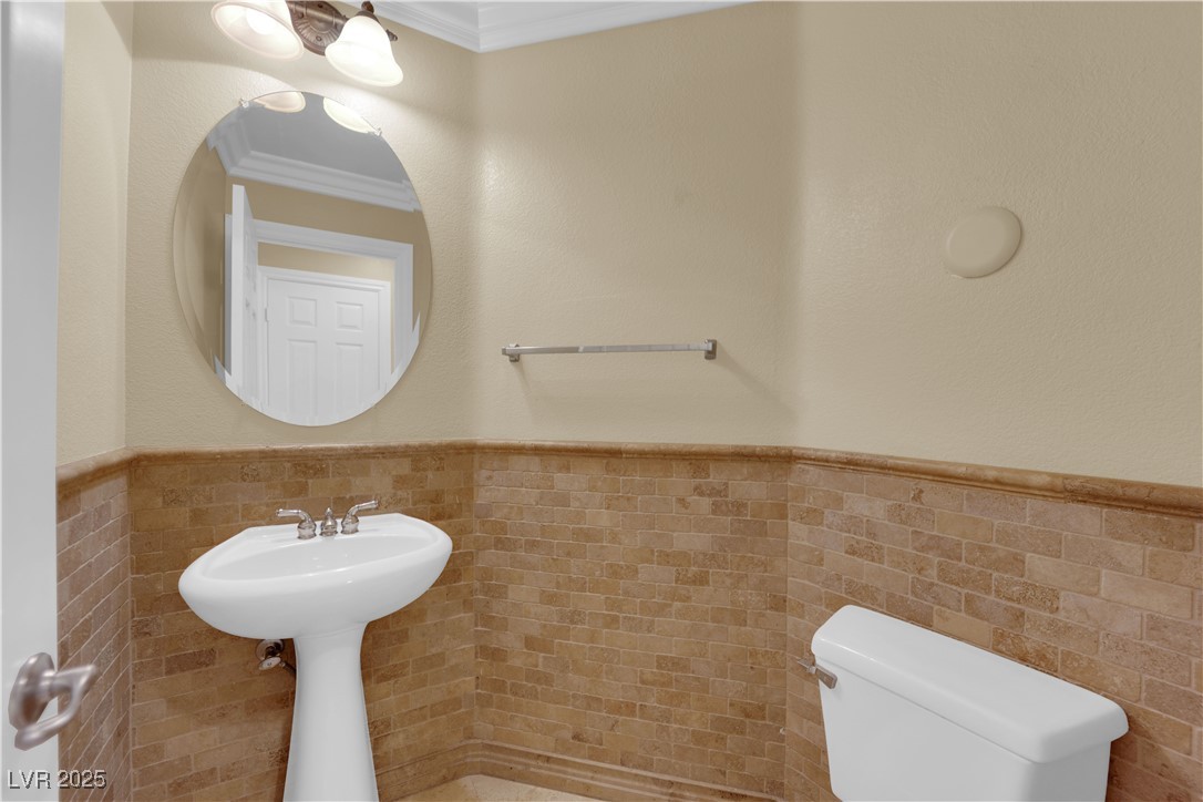 10057 Portula Valley Street Las Vegas, NV 89178 - Photo 25 of 56 Bathroom featuring tile walls, wainscoting, ornamental molding, and a textured wall