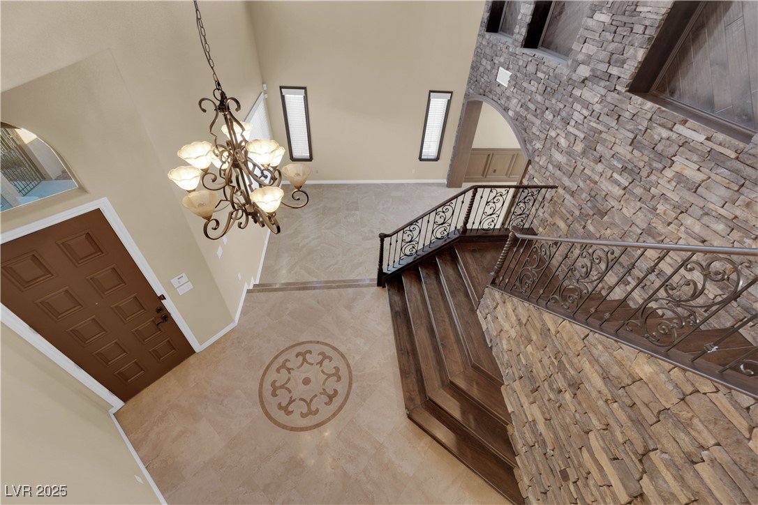 10057 Portula Valley Street Las Vegas, NV 89178 - Photo 29 of 56 Foyer entrance featuring a towering ceiling, tile patterned floors, arched walkways, and a chandelier