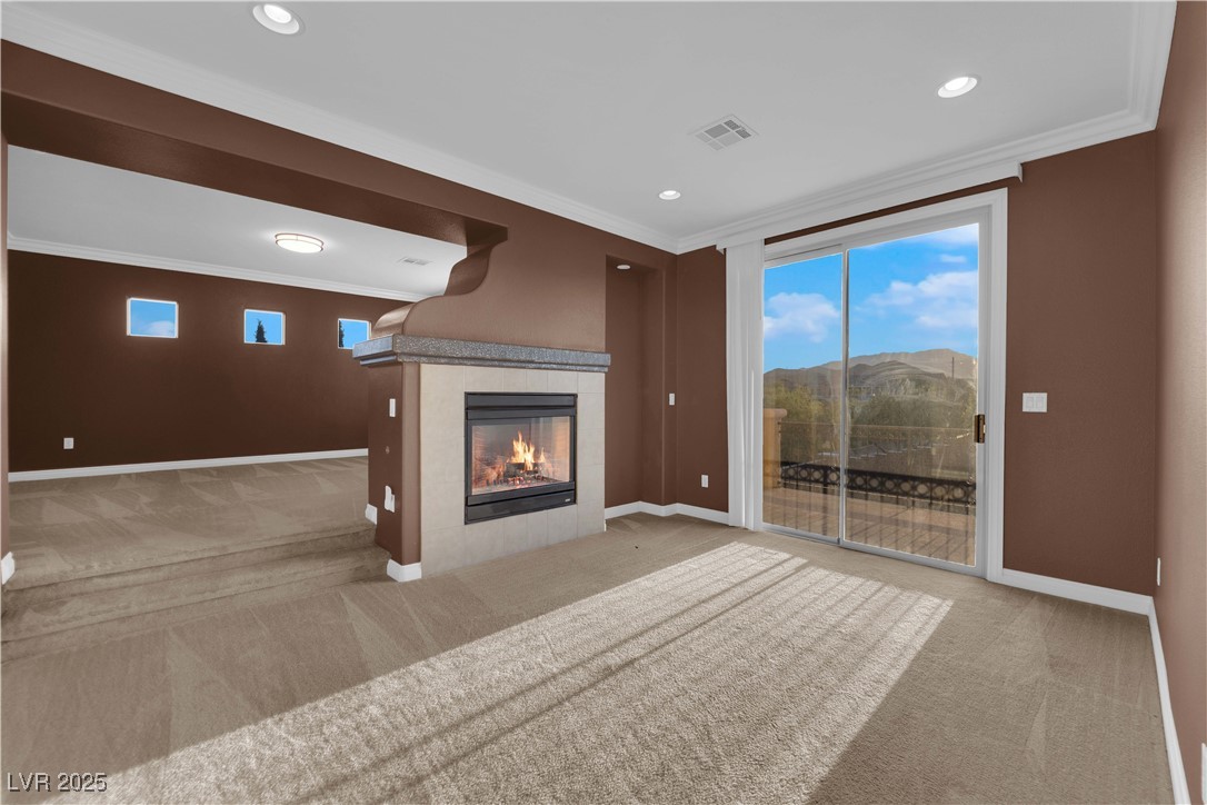 10057 Portula Valley Street Las Vegas, NV 89178 - Photo 30 of 56 Unfurnished living room with light colored carpet, crown molding, a fireplace, and recessed lighting