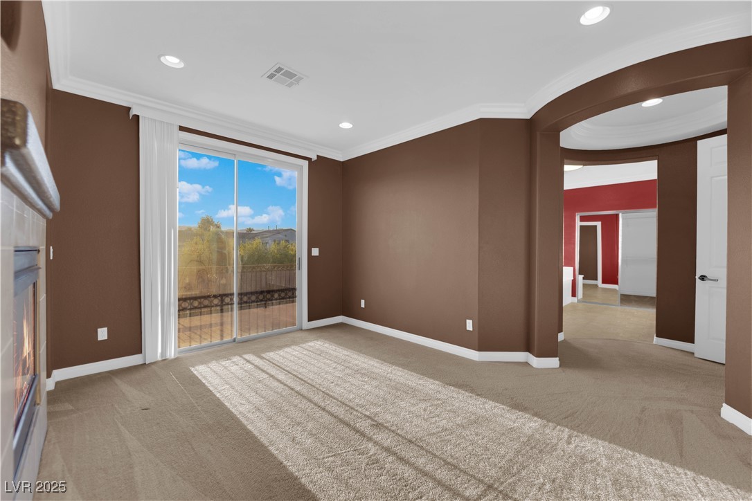 10057 Portula Valley Street Las Vegas, NV 89178 - Photo 33 of 56 Empty room with light carpet, a fireplace, crown molding, recessed lighting, and arched walkways