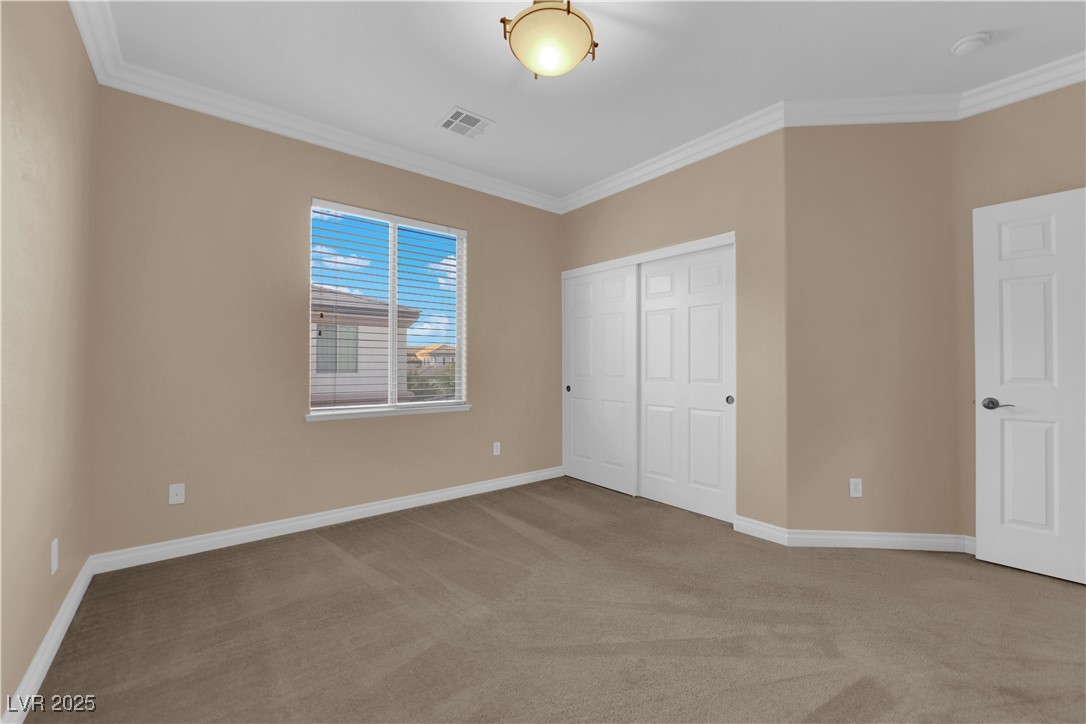 10057 Portula Valley Street Las Vegas, NV 89178 - Photo 38 of 56 Unfurnished bedroom featuring ornamental molding, light carpet, and a closet