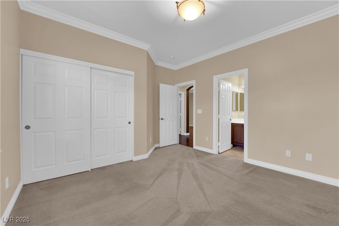 10057 Portula Valley Street Las Vegas, NV 89178 - Photo 39 of 56 Unfurnished bedroom featuring crown molding, light carpet, a closet, and connected bathroom