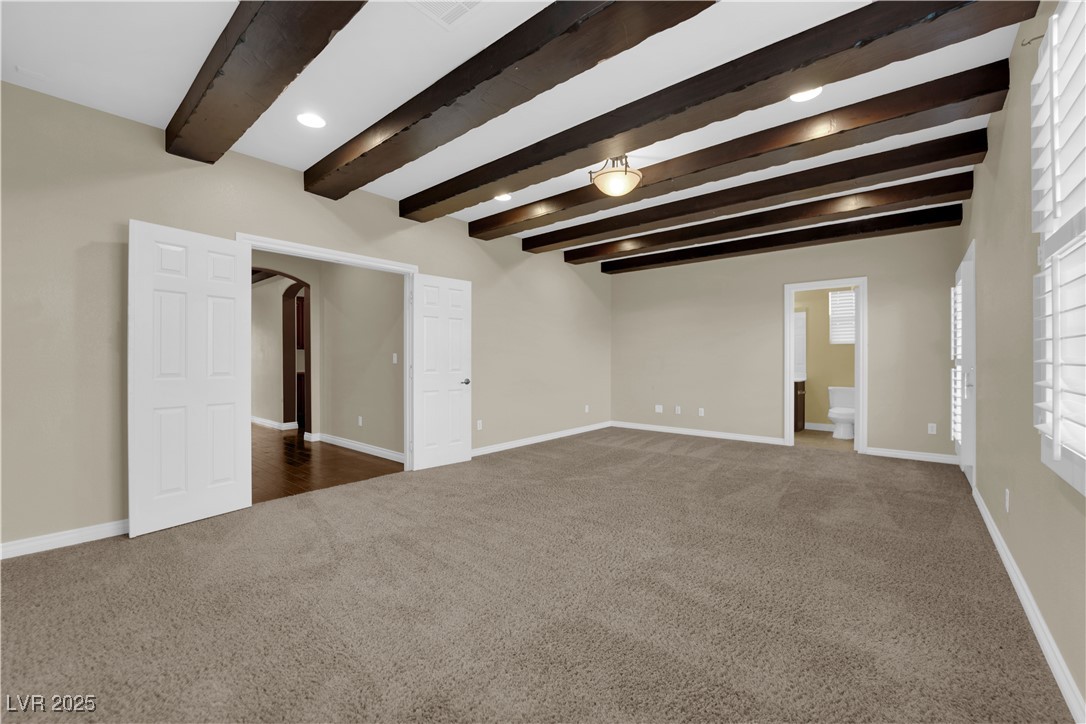 10057 Portula Valley Street Las Vegas, NV 89178 - Photo 46 of 56 Empty room featuring beamed ceiling, dark carpet, and arched walkways
