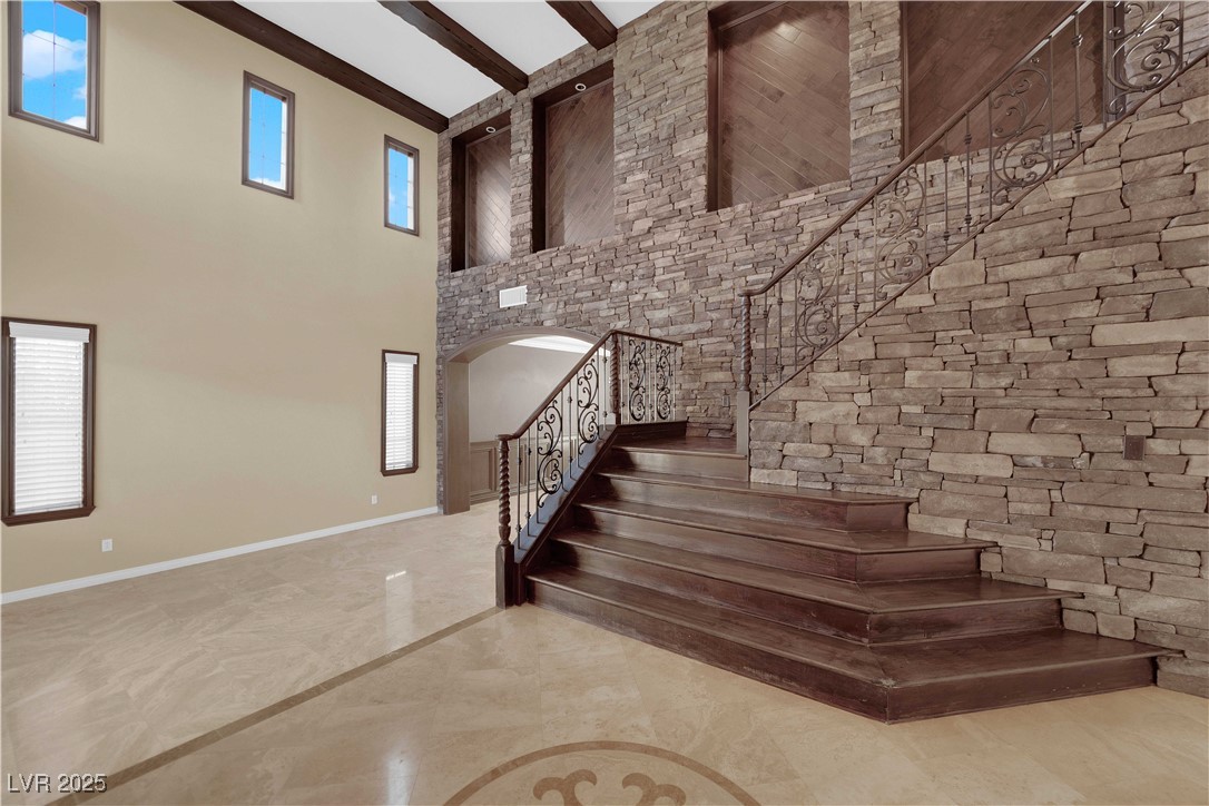 10057 Portula Valley Street Las Vegas, NV 89178 - Photo 7 of 56 Staircase with beamed ceiling, a towering ceiling, and arched walkways