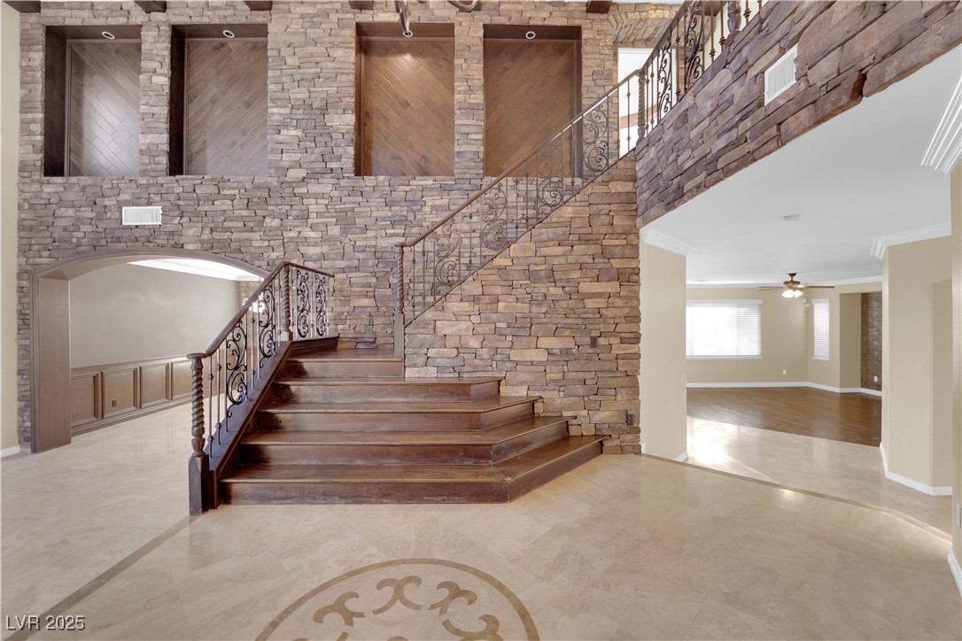 10057 Portula Valley Street Las Vegas, NV 89178 - Photo 8 of 56 Staircase with ornamental molding, a high ceiling, a ceiling fan, and arched walkways