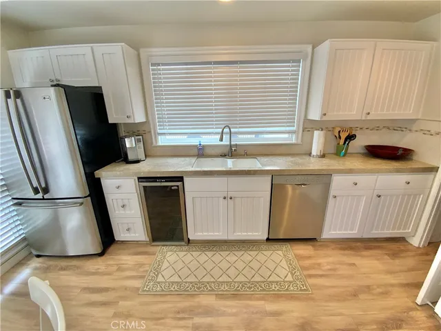 a kitchen with stainless steel appliances a stove a sink a refrigerator a window wooden floor and cabinets