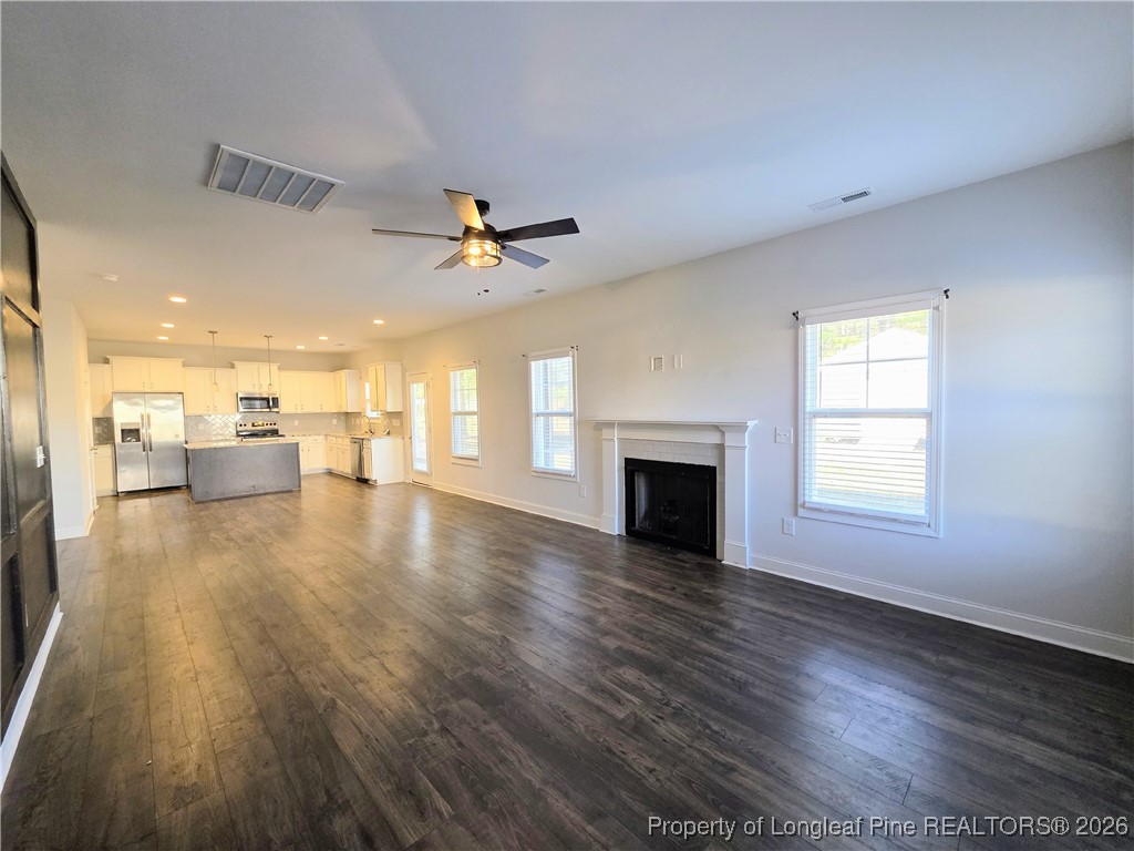 7850 Rufus Johnson Road Fayetteville, NC 28306 - Photo 5 of 25 a view of a livingroom with a fireplace a ceiling fan and windows