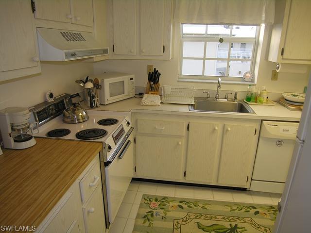 1051 3rd Street South, Unit 301 Naples, FL 34102 - Photo 12 of 15 a kitchen with sink a stove and cabinets