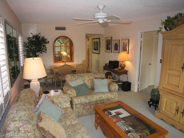 1051 3rd Street South, Unit 301 Naples, FL 34102 - Photo 8 of 15 a living room with furniture a chandelier and a flat screen tv