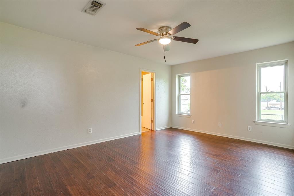 709 North Ave B Springtown, TX 76082 - Photo 22 of 32 an empty room with wooden floor chandelier fan and windows